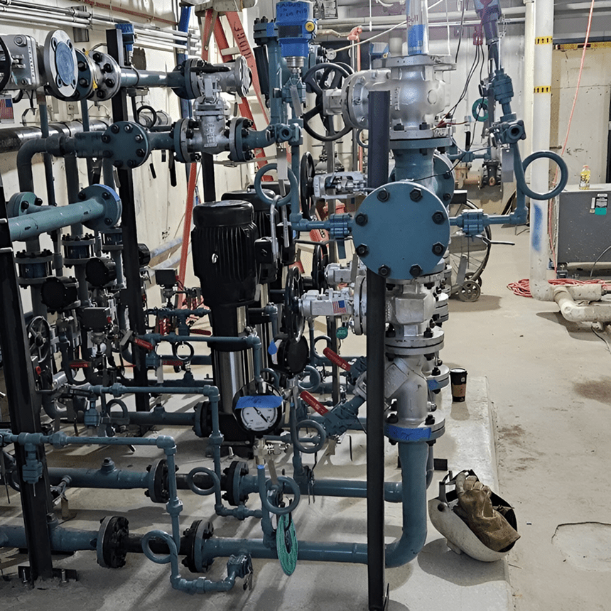 Industrial pipes and valves in mechanical room.