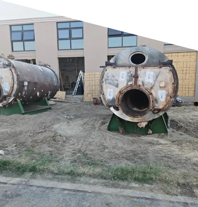 Two large rusty industrial tanks outdoors near a building.